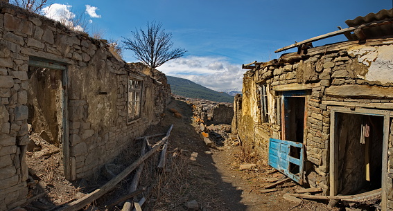Russia. North-Eastern Caucasus,  Dagestan. View of the Caucasus Mountains through the doorway of an abandoned house in the mountain village of Khushtada. Traditionally, all houses are made of stone.