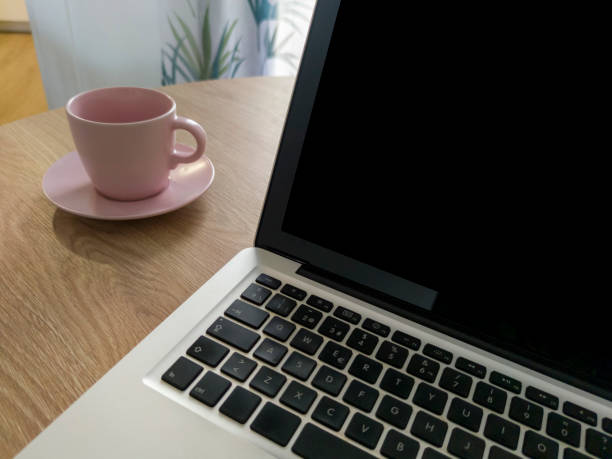 Living room table with laptop and pink blush mug. Domestic workspace concept