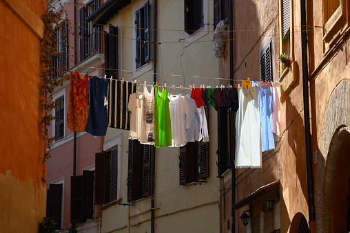 Traditional method to dry clothes hanging them on a line between two buildings across a street in Rome