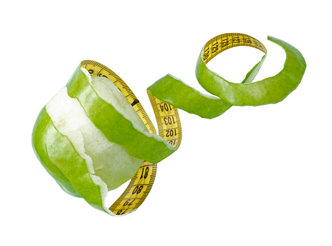 Green Apple peeled with twisting skin as measuring tape on white background. Concepts of Healthy lifestyle.