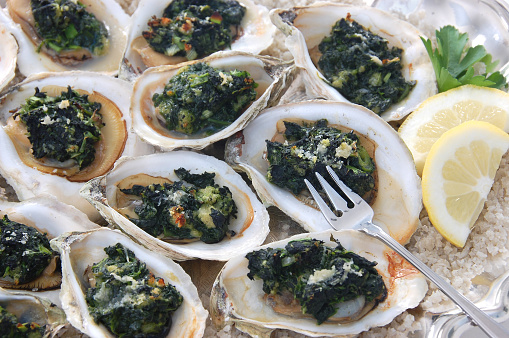 A classic appetizer, baked oysters topped with a mix of greens, butter, and cheese, \