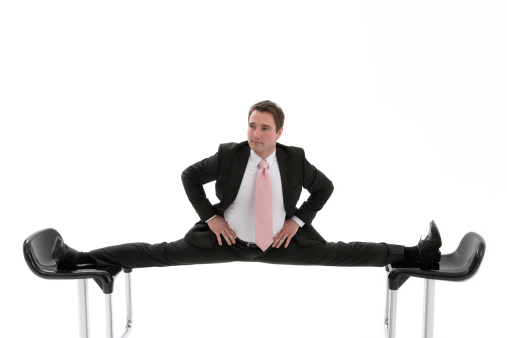 Manager doing the splits between two chairs.Oftly an uncomfortable situation in office.