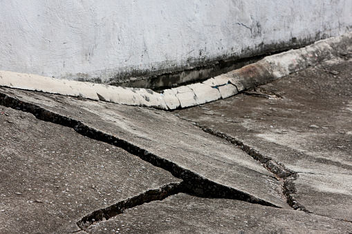 Concrete road subsidence showing serious cracks and damage. Shallow depth of field.