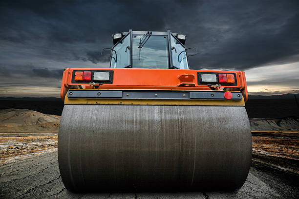 Big orange road roller upon a cloudy sky stock photo