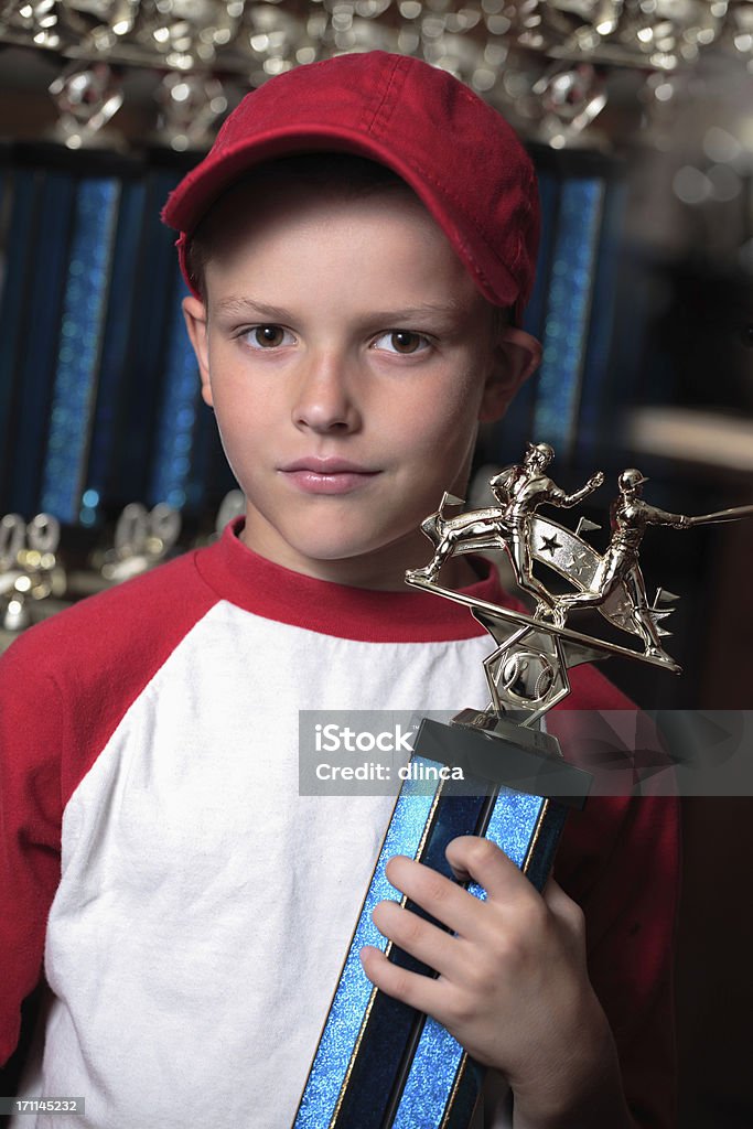 Boy with championship baseball trophy Young boy grinning while holding a large baseball trophy.  Other identical trophies for his team can be seen in the background. Award Stock Photo