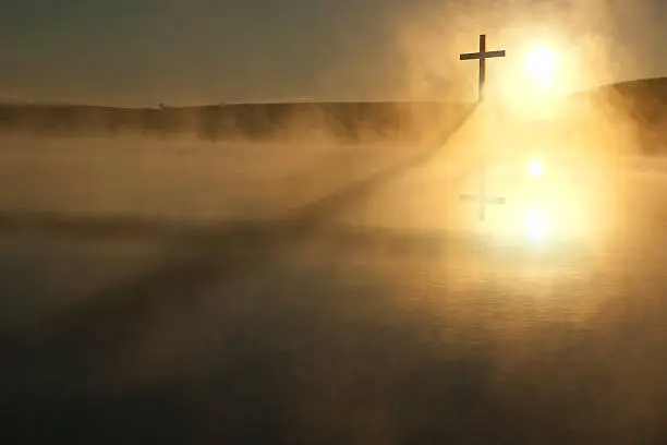 Photo of Single Cross Long Shadow Sunrise on Foggy Lake Easter Morning