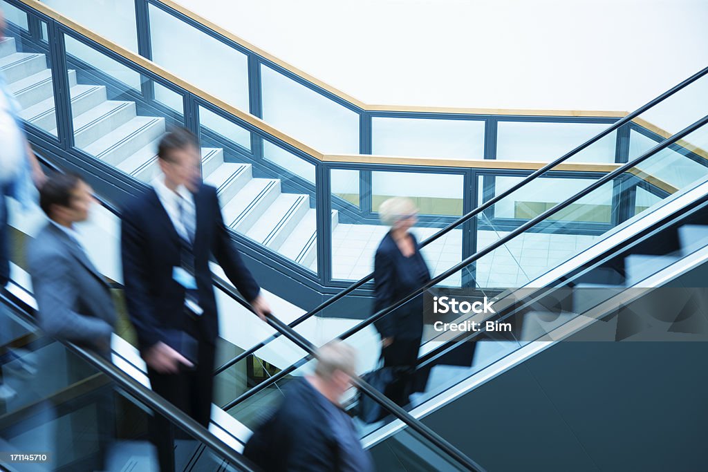 Gente de negocios en movimiento borroso en escaleras mecánicas, - Foto de stock de Actividades bancarias libre de derechos