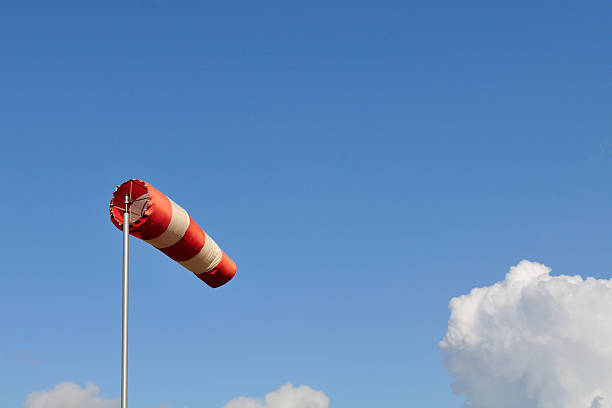 rojo y blanco viento calcetín contra un cielo azul. - meteorology weather vane direction wind fotografías e imágenes de stock
