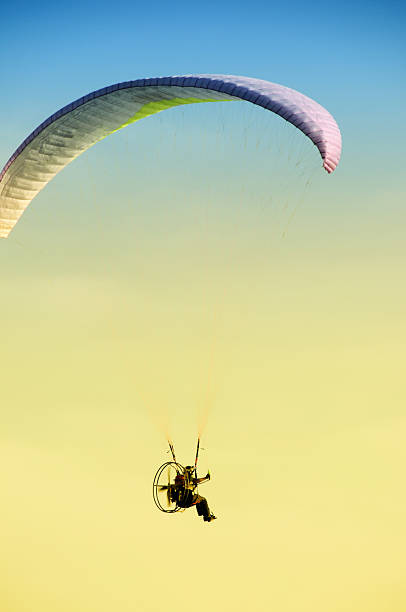 Paraglider moving with Propeller Paraglider riding alone in the sky on sunrise. para ascending stock pictures, royalty-free photos & images