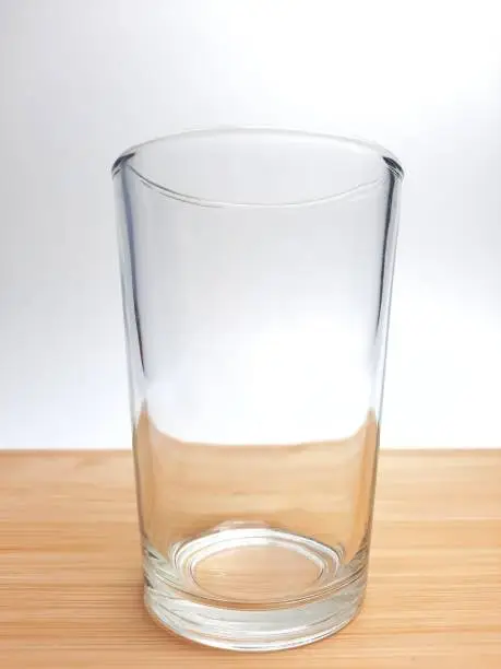 Photo of Empty drinking glass cup with copy space. Glass cup with wooden coaster