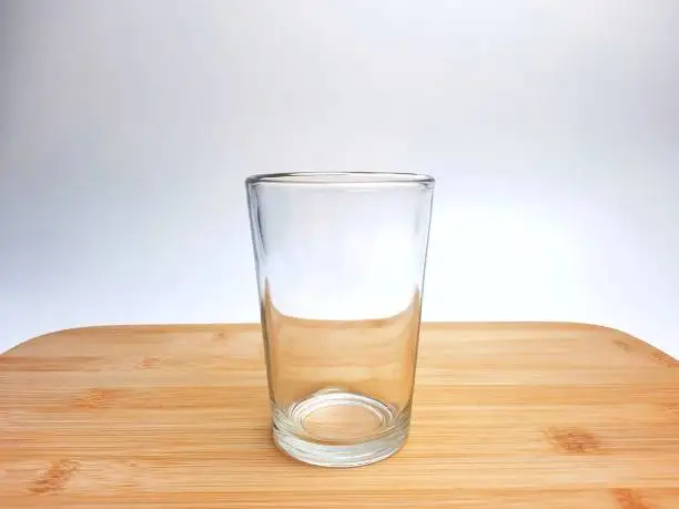 Photo of Empty drinking glass cup with copy space. Glass cup with wooden coaster