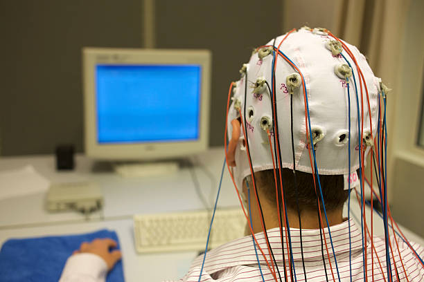 man connected with cables for EEG in front of monitor for a scientific experiment, a man connected with cables to a computer sits in front of a screen, EEG for research eeg stock pictures, royalty-free photos & images