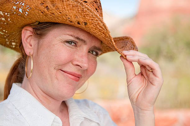 A beautiful mature woman in her 40s with a cowboy hat and flawless complexion.