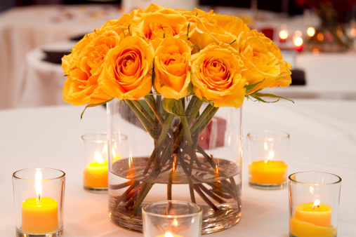 Wedding Bouquet on Table with Votive Candles Yellow FlowersThis table at a wedding reception is decorated with small yellow candles and a yellow rose centerpiece.