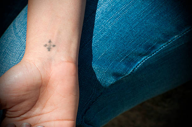 Coptic cross tattoo on young Egyptian woman's wrist A young Egyptian woman shows the Coptic cross tattoo on her wrist, which is found on most of the several million Coptic Orthodox Christians in Egypt. wrist tattoo stock pictures, royalty-free photos & images