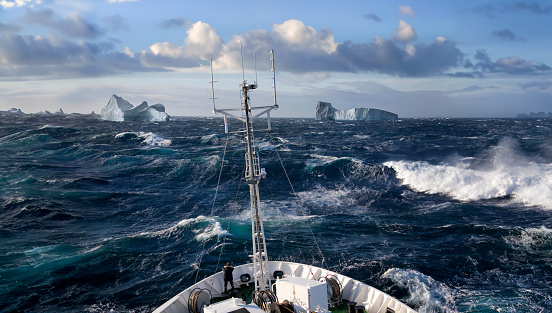 Ship rolling in heavy seas near icebergs in Scoresbysund on the east coast of Greenland.