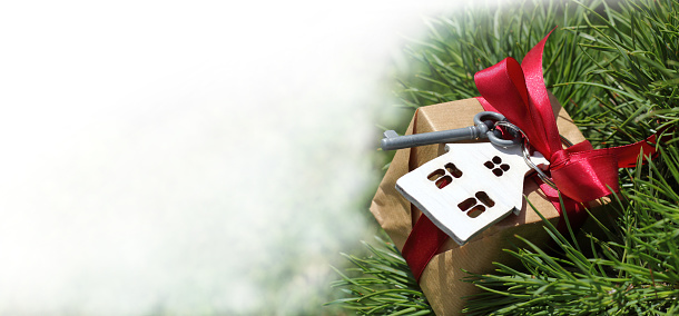 gift with a key and a house on the background of an evergreen tree