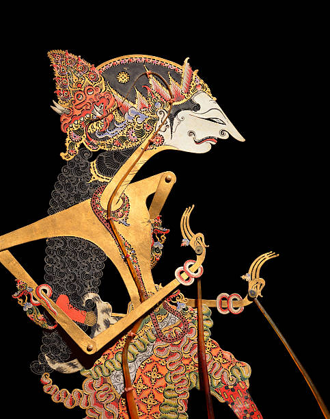 Wayang Puppet Javanese shadow puppet on black background. These puppets (Bali, early 20th century), made of buffalo hide, are used in wayang kulit aEshadow puppet playaa. The term 'wayang' was derived from Javanese word for "shadow". Wayang Kulit plays are invariably based on romantic tales, especially adaptations of the classic Indian epics, "The Mahabarata" and "The Ramayana". mahabharata stock pictures, royalty-free photos & images