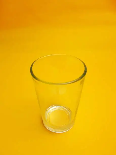 Photo of Empty glass isolated on yellow background