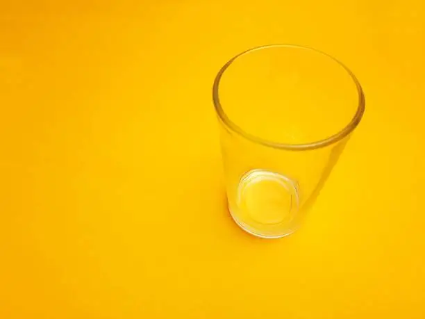 Photo of Empty glass isolated on yellow background