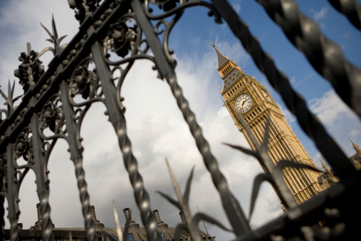 The iconic Big Ben tower, symbol of UK government, captured between the bars of the Houses of Parliament.