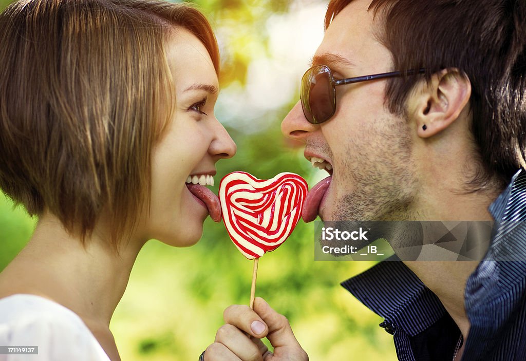 Couple in love licking a lollipop Couple in love licking a lollipop. Sunshine and happiness Heart Shape Stock Photo