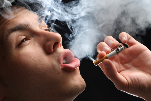 Smoking cigarette, smoke coming from mouth of young man