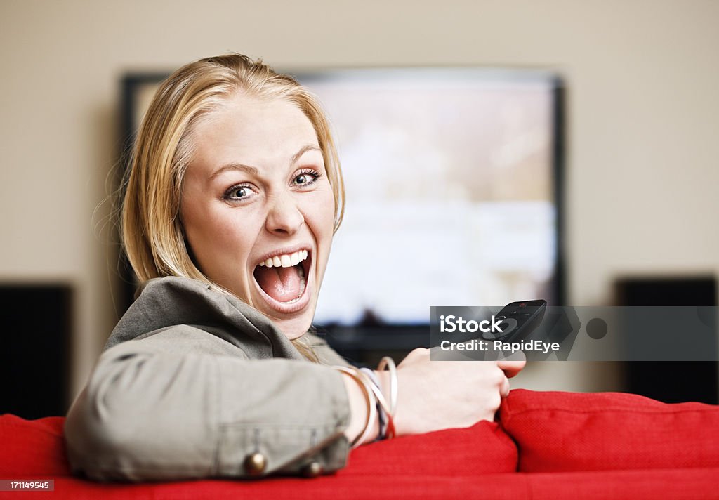 Linda loira laughs – ela tem o controle remoto da TV! - Foto de stock de Controle Remoto royalty-free
