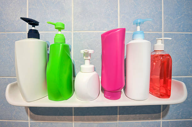 Many shampoo and soap bottles on a bathroom shelf. stock photo