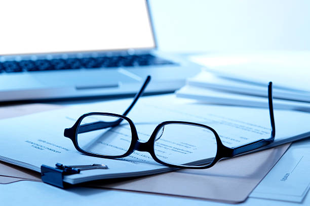 istock Blue tinted image of stacked document with laptop and glasses 171150289