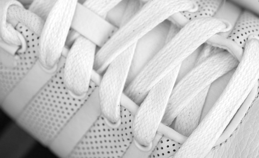 Hands cleaning a white sneaker, with out of focus background