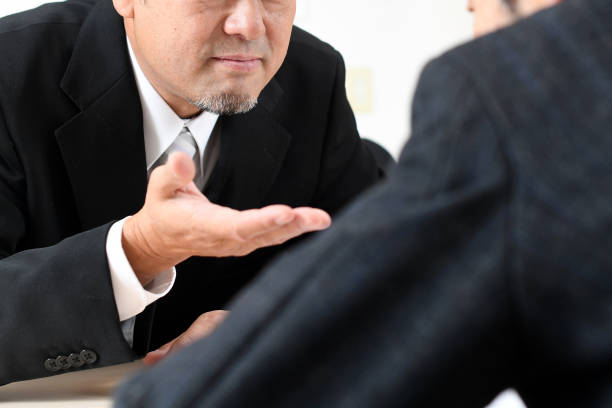 istock Middle-aged Asian businessman in a suit talking privately 1711512441
