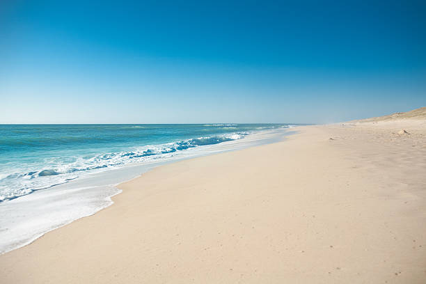 A scenic view of a beach with sand and blue water stock photo
