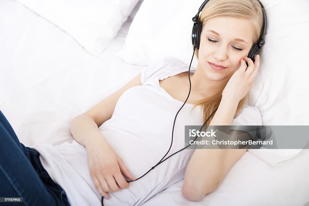 Jovem mulher ouvir para auscultadores na cama - Royalty-free Auscultador - Equipamento Áudio Foto de stock