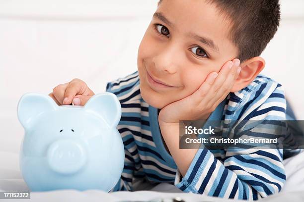 Lächelnde Junge Putting Geld Im Sparschwein Stockfoto und mehr Bilder von 6-7 Jahre - 6-7 Jahre, Asiatischer und Indischer Abstammung, Auf dem Bauch liegen