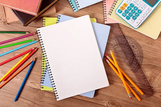 Student's desk with open notebook, text books, various pencils and calculator.  Alternative version shown below: