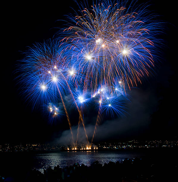 Blue and orange fireworks at night over a lake stock photo