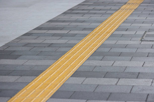 yellow tactile tiles are installed on outdoor pedestrian walkways to provide tactile ground surface indicators, aiding individuals who are blind or visually impaired. These detectable warnings are designed to assist outside. las baldosas táctiles amarillas se instalan en las pasarelas peatonales al aire libre para proporcionar indicadores táctiles de la superficie del suelo, ayudando a las personas ciegas o con discapacidad visual. estas advertencias detectables están dise�