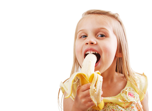 a little girl eating a banana isolated on white.