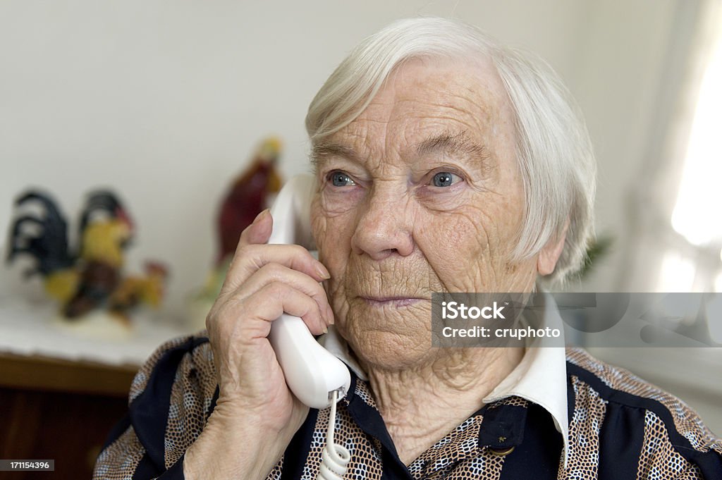 Female Senior is holding a phone and looks sad Old Granny gets a sad message transmitted on the telephonePlease see some similar pictures in this Lightbox: Landline Phone Stock Photo