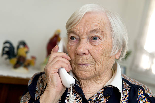 Female Senior is holding a phone and looks sad stock photo