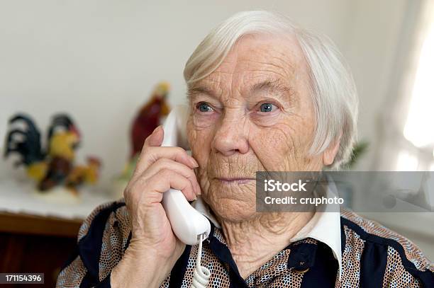 Female Senior Is Holding A Phone And Looks Sad Stock Photo - Download Image Now - Landline Phone, Senior Women, Telephone