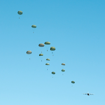 Air drop of paratroopers from C-130 airplane during a military training exercise.