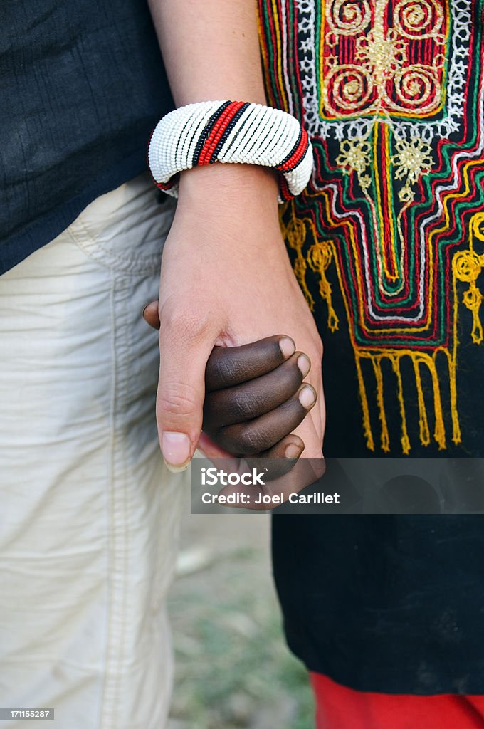 White and black people holding hands A caucasian girl holds hands with a younger African girl in an Ethiopia village. Ethiopia Stock Photo