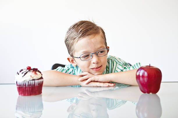 rapaz escolher entre uma maçã e de bolinho - cake pick imagens e fotografias de stock