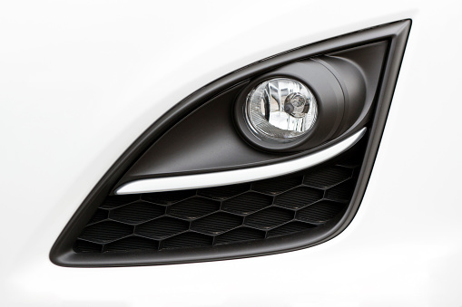 The front of the white commercial van car with a dipped beam headlight close-up