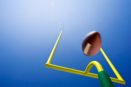 Field Goal or Extra Point in American Football looking up at the goal post as the ball flies through the air in motion
