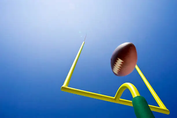 Field Goal or Extra Point in American Football looking up at the goal post as the ball flies through the air in motion