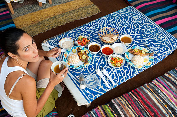 Traveler eating dinner in Egypt A female traveler sits at a seaside restaurant for a mealin Dahab, Egypt. Among the items on the table: fish, rice, vegetables, soup, bread, and tahina. dahab photos stock pictures, royalty-free photos & images