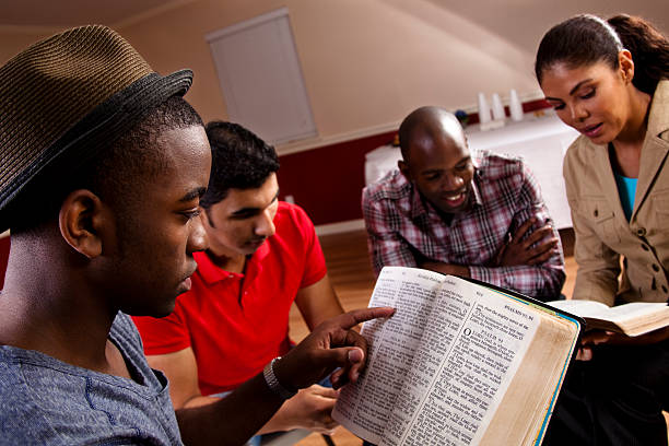 Young adults, multi-ethnic group in a Bible study at church. Young adults meeting together in a Bible study. They are in Church fellowship hall.  Multi-ethnic group. Latin, African descent people.  Bible stock pictures, royalty-free photos & images